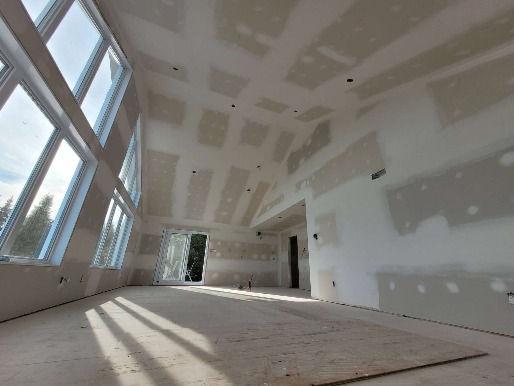 Finition de gypse d'un plafond cathédrale avec grandes fenêtres, lumière naturelle sur les joints tirés