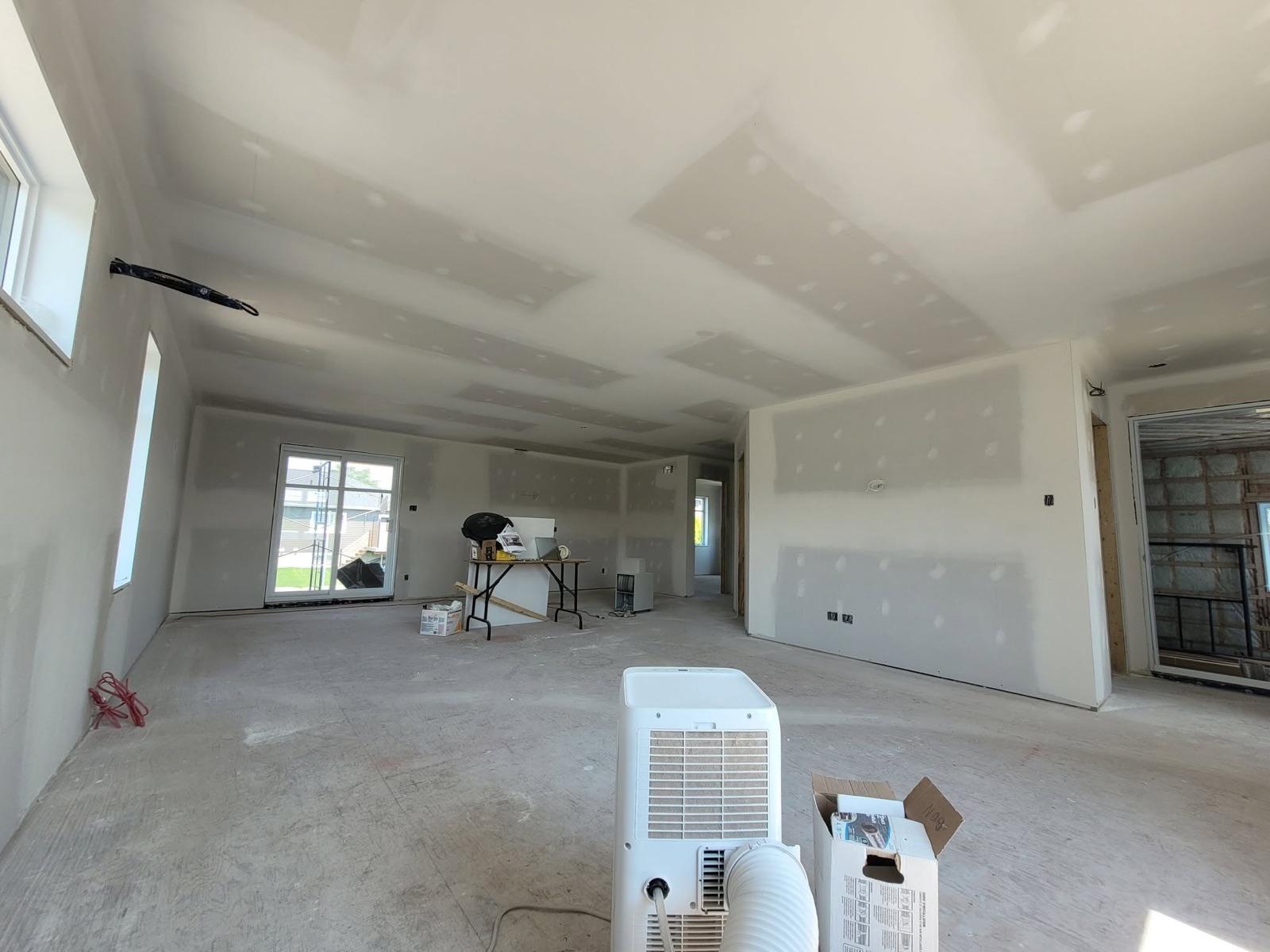Finition de gypse d'une aire ouverte dans une maison neuve, murs et plafond prêts à peindre